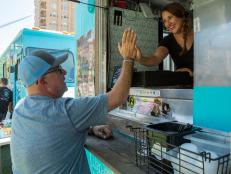 Host Andrew Zimmern high-fives co-owner Desiree Broderick at the Havana Eats, a Cuban street food inspired food truck, as seen on Big Food Truck Tip, Season 1.