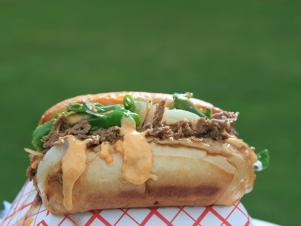 Bulgogi Philly Cheesesteak (Marianated shaved beef topped with sauteed onions, shishito peppers, kimcheese sauce on hoagie roll) on table at Ajumama, as seen on Comfort Food Tour, Season 2.