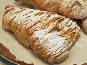 A giant Lobster Tail pastry dusted with powedered sugar at Maria's Pastry Shop as seen on Food Network's Baked, Season 1.
