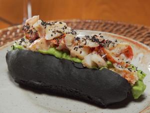 Pagu's twist on the Lobster Roll features a roll colored by squid ink and topped with chucks on fresh lobster as seen on Food Network's Baked, Season 1.
