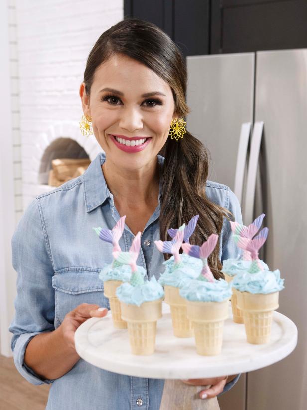 Host Brandi Milloy poses with her Mermaid Cupcake Stuffed Ice Cream Cones are displayed, as seen on Let's Eat, Season 1.
