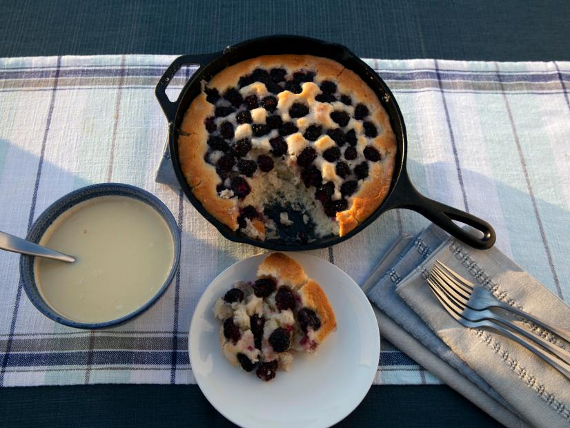 Fresh baked Blackberry Cobbler in a cast iron skillet is served up piping hot with creamy Sassy Sauce on Cajun Aces