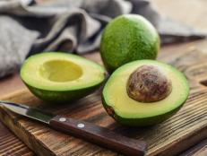 Fresh avocado on cutting board over wooden background