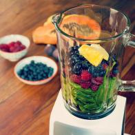 Fruits and vegetables as ingredients for a healthy smoothie: papaya, figs, lemon, blueberries, pomegranate seeds, raspberries, pineapple and baby spinach