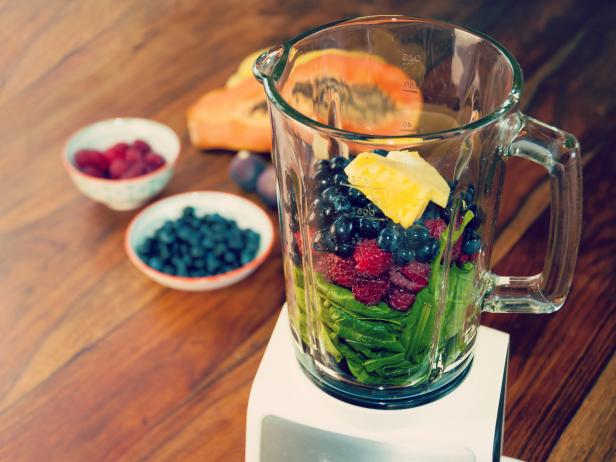Fruits and vegetables as ingredients for a healthy smoothie: papaya, figs, lemon, blueberries, pomegranate seeds, raspberries, pineapple and baby spinach