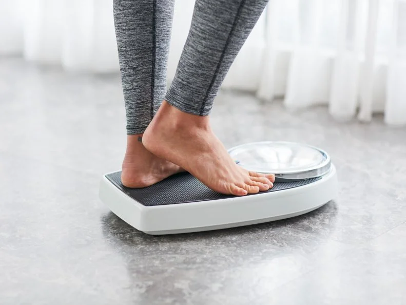 Young healthy girl on home scales