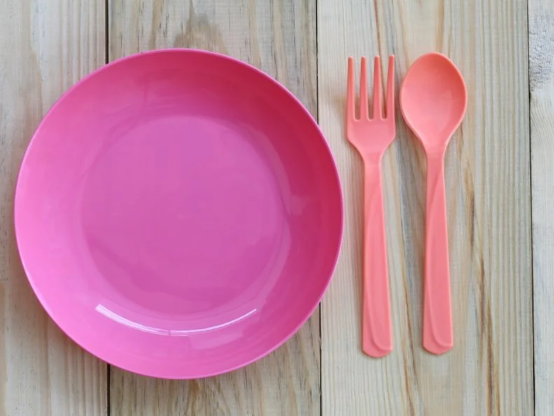 Empty pink plastic dish and spoon placed on wooden floor and have copy space for design in your work.