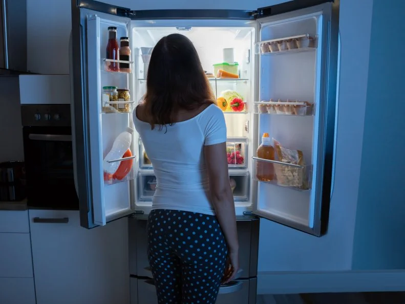 Rear View Of Young Woman Looking In Fridge At Kitchen