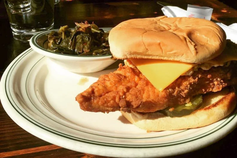 As evidenced by countless fast food joints and chef-driven fast-casual spots, fried chicken sandwiches are one of America's favorite ways to get covered in grease. There are plenty of options for great fried chicken sandwiches, but Buxton Hall BBQâ  s rendition has reached road trip-worthy status. Pitmaster Elliot Moss smokes his bird along with his acclaimed whole hog, then dips each breast in buttermilk, before itâ  s deep-fried and topped with a combination of American and pimento cheeses, white barbecue sauce and bread-and-butter pickles. The creamy, smoky and crisp ingredients are sandwiched between a toasted white bun that somehow manages to hold it all together.