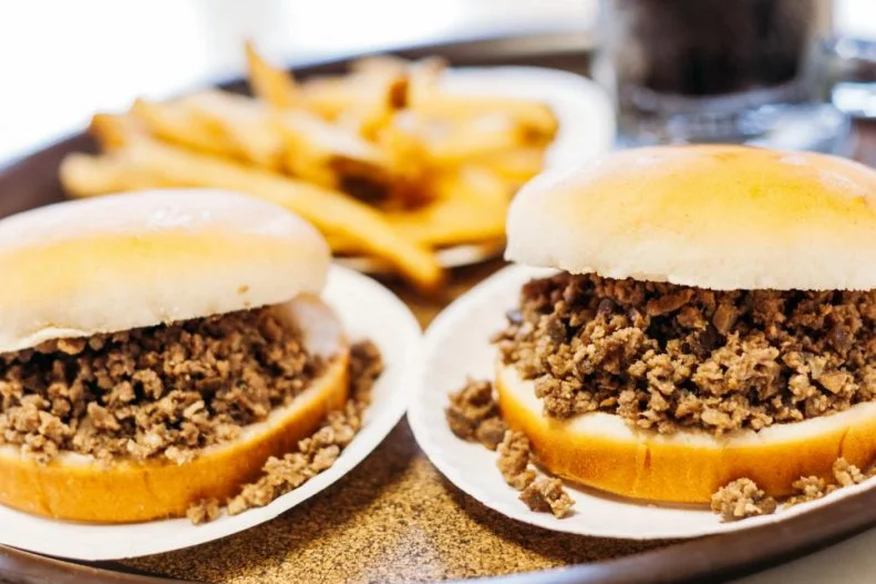 An Iowa tradition since 1926, chowing down on a Maid-Rite sandwich is a requirement for sandwich-loving Hawkeyes. The messy ground-meat sandwich â   with Midwestern beef topped with mustard, ketchup, onion and pickles on a fresh-steamed bun â   was first invented by butcher Fred Angell in Muscatine, Iowa. A customer, a local delivery man, was pleasantly surprised by that combination of tangy spices and savory meat, declaring the combination to be â  made right.â   And the sandwich got its name. Shortly after its inception, Angell began franchising the concept, spreading the gospel of the Maid-Rite sandwich across the state and throughout the entire Midwest.
