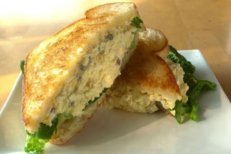 The egg salad sandwich has long filled the void when it seems like thereâ  s nothing to eat in the house. Even the most sparsely populated kitchens tend to have eggs, mayo and some sort of bread. Chef Justin Brunson of Masterpiece Deli in Denver kicked the classic fridge forager dish up several notches. Drawing on the chef-beloved egg-and-truffle pairing, Brunson added high-quality white truffle oil. Served on butter-toasted white bread, the fairly straightforward recipe (which can be found with a simple google search) blends hard-boiled eggs with mayo, capers, red onion, Kosher salt and ground black pepper layered with a bed of crisp Romaine lettuce.