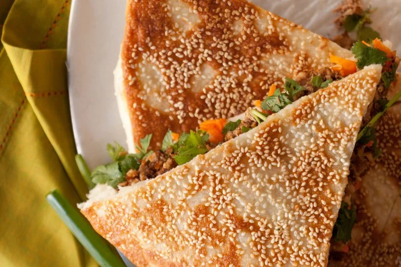 Following in the footsteps of the enterprising immigrants who adapt homeland favorites to local customs, Vanessa Weng created the ultimate mashup dish of Beijing and New York City. She took the former’s breakfast staple, the sesame pancake, and reinvented it as a sandwich. Like the street food vendors in Northern China, Weng fries her pancake-like dough on an oiled pan until the sesame-studded mixture is crisp on the outside, spongey within. It’s filled with julienned cucumbers, green onions, sprigs of cilantro and flavorful fillings ranging from kimchi and egg to Szechuan-style beef and Peking duck.