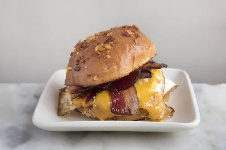New York City may be best-known to out-of-towners for its dollar slices and dirty water dogs. However, one of the most popular locally beloved staples is the bacon, egg and cheese on a roll. Itâ  s not an exaggeration to say that there are hundreds, if not thousands, of excellent BEC found at bodegas and delis throughout the city, whipped up in under a minute. For a grand take on the morning mainstay, head to the fittingly labeled BEC. The Chelsea fast-casual joint offers made-to-order organic egg sandwiches accented with locally sourced meat and dairy. The BEC Classic combines two over-easy eggs with applewood-smoked bacon and New York sharp cheddar on a bacon- and cheese-crusted brioche bun.
