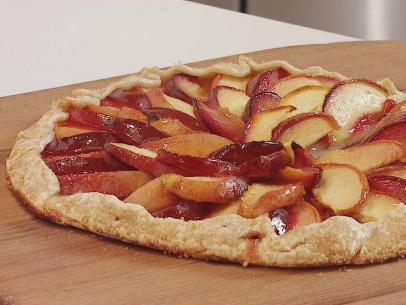 Peach and Plum Galette prepared by food and lifestyle expert Brandi Milloy, made with fresh peaches and plums cut into slices. In a mixing bowl  Brandi adds powedered sugar, cornstarch, and a little almond extract mixed together. Peach Jam added to dough which will give you a barrier for thin crust and make the placement of your peaches and plums easier, close dough edges with little pinches, egg wash, sprinkled with turbanoto sugar aka thicker sugar, baked 400 degrees for 30 minutes, ready to serve,  as seen on Food Network Lets Eat Ep 108.