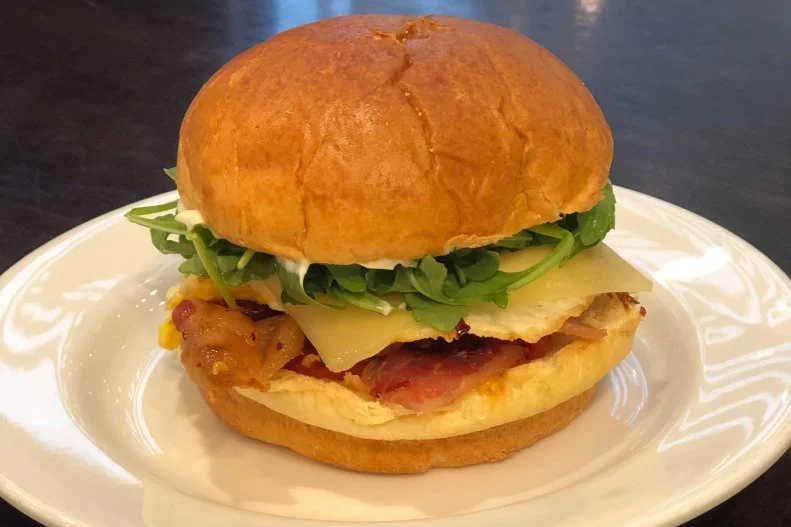 The Goddess has always been a great place to grab and go, but with the addition of the maple bacon sandwich, a little lingering may be in order. The sandwich is made on a brioche bun with a fried egg, melted GruyÃ¨re cheese, housemade maple-chile bacon, and a sweet and spicy roasted tomato jam. It's topped off with fresh arugula and a lemon-rosemary aioli to balance the heat.