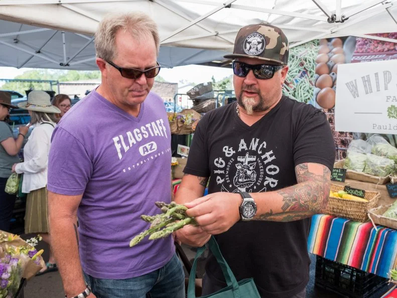 Guy Fieri picks up asparagus at the Flagstaff Community Farmers Market, as seen on Guy's Family Road Trip, Season 1.