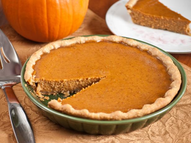 A pumpkin pie with a wedge cut out and sitting on a plate for serving.More homemade pies: