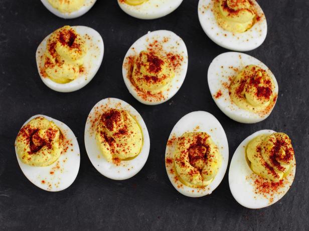 Homemade Spicy Deviled Eggs with Paprika on a plate of black slate