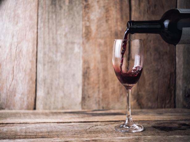 pouring wine into glass on wood background