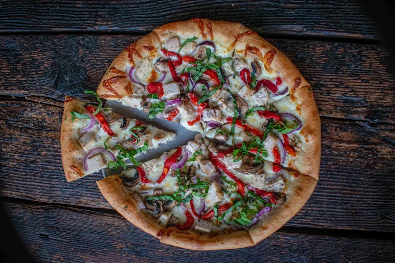Old Town Pizza & Brewing was founded in 1974 in the lobby of the Merchant Hotel, one of Portland’s oldest buildings. Place your order at the window (formerly the hotel’s reception desk) for signature pies like the O.G. house special, which stars pepperoni and homemade Italian sausage. But don’t be surprised if Nina (pronounced “Nigh-na”) joins you for a slice. She’s been around for over a century and is often spotted donning a black dress. She’s been known to wander the basement (one delivery driver asked to be taken off the brewery’s route after seeing her here) or observing diners (if she gets really closed, you might catch a whiff of perfume). Despite the Merchant Hotel being an upstanding institution in town, it was also known for its prostitution. Local legend has it that one of the working girls, Nina, was murdered and left in the elevator shaft (which is now the backdrop of one cozy booth in the back of the restaurant). Pay homage to Nina with the ghost pie, in which beer-marinated chicken sits atop an alfredo-sauced base scattered with roasted red pepper and mushrooms.