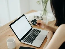 Woman with credit card and laptop paying bills online  at home