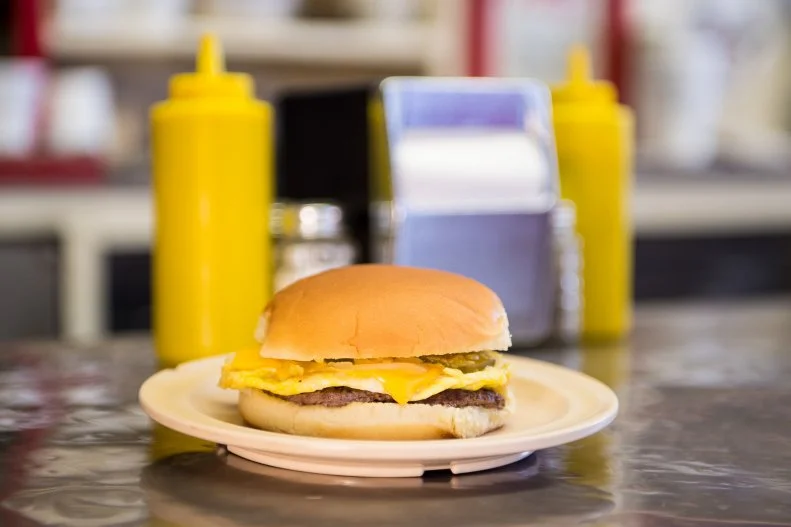 "We seat 1,000 people, 10 at a time." It's one of the first signs you'll notice when you step inside the Texas Tavern, a tiny 24/7 joint that's served Roanoke since 1930. The sign is right: There are just 10 red stools along the stainless-steel counter, and the original stainless-steel pipe foot rail is worn halfway through by the decades' worth of shoes that have rested on it. The sign is also a nod to the brand of quirky humor that's become as signature to the tavern as its homemade meat-and-bean chili (whose name is spelled with an "e" here) and the Cheesy Western, a hamburger topped with a scrambled egg, cheese and homemade relish. Texas Tavern is also locally known as Roanoke's Millionaire's Club; everyone is treated like a millionaire here, and food is dished up with a side of banter (and a hearty helping of BS) from the guys behind the counter. Many of them have worked here since the 1980s and know regulars' orders by heart, but it doesn't hurt if you know the shorthand lingo for ordering: A "bowl" simply means chili, while a "bowl with" means it'll come topped with diced onions; "hot" refers to a hot dog, which comes topped with a rich, beanless chili (fourth-generation owner Matt Bollington likes adding it to his Cheesy Western). Ask for your dog "walking" to get it to go, and don't even think about asking for ketchup — unless you want to catch flak for getting "sissy sauce."