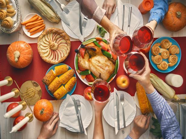 Happy Thanksgiving Day! Autumn feast. Family sitting at the table and celebrating holiday. Traditional dinner. Grandparents, parents and children. Hands and cheers. Top view.