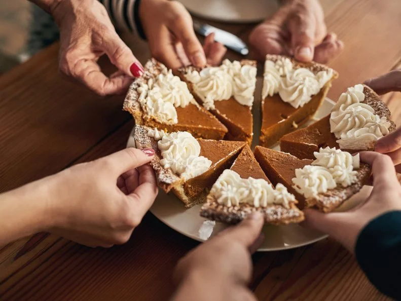 Shot of a group unrecognizable people's hands each taking a slice of cake on a dinner table
