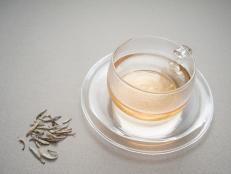 A hot cup of silver needle white tea scented with jasmine blossoms with those precious unbrewed tea leaves on the side.