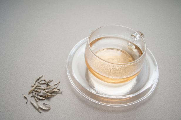 A hot cup of silver needle white tea scented with jasmine blossoms with those precious unbrewed tea leaves on the side.