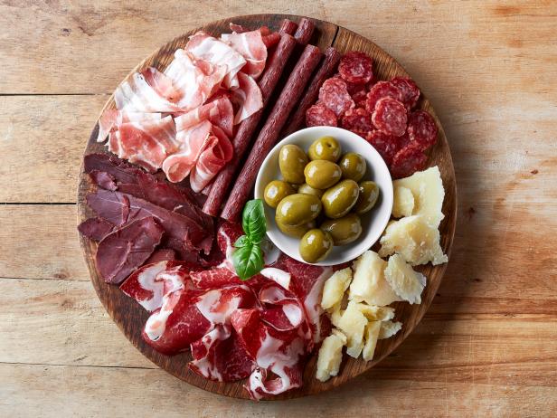Cold smoked meat plate with prosciutto, salami, bacon, cheese and olives on wooden background. From top view