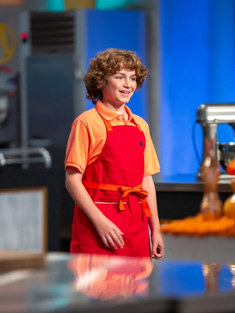 Anthony standing in front of judges table, as seen on Kids Baking Championship, Season 8.