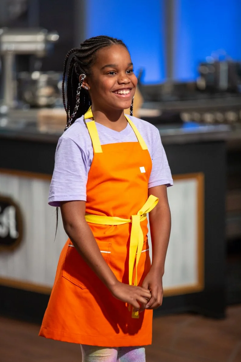 Naima standing in front of judges table, as seen on Kids Baking Championship, Season 8.