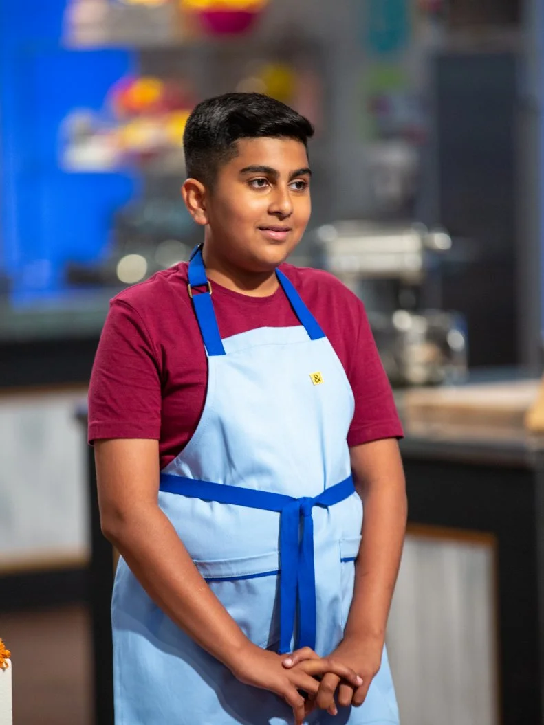 Saleem standing in front of judges table, as seen on Kids Baking Championship, Season 8.