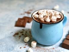 Homemade hot chocolate with mini marshmallow in a blue enamel mug on a light slate background.Rustic style.