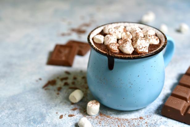 Homemade hot chocolate with mini marshmallow in a blue enamel mug on a light slate background.Rustic style.