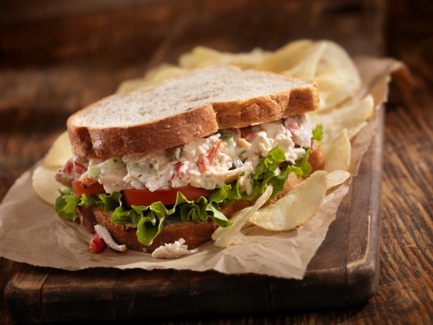 A Creamy Chicken Salad Sandwich with Red Peppers, Cucumber, Lettuce and Tomato on Whole Wheat Bread and Potato Chips on the side- Photographed on Hasselblad H3D2-39mb Camera