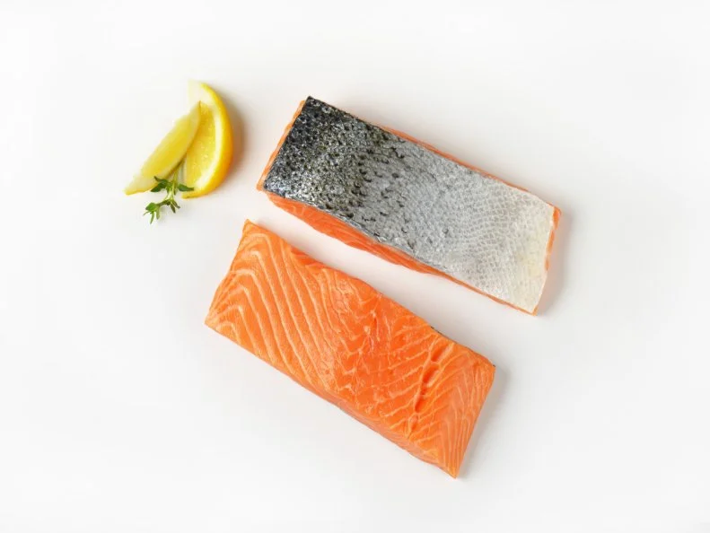 Two raw salmon fillets and lemon on white background