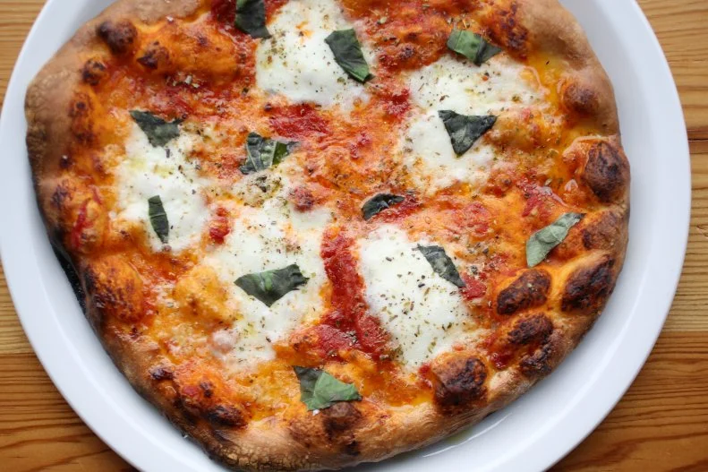 Anyone can put pizzeria in the name of their restaurant, but you know it's going to be good pizza when you can smell it before you even taste it. A Wood Stone pizza oven anchors the Pizzeria Toro space, emitting an intoxicating aroma of dough baking and charring. Here, the pizza dough is crafted from a blend of soft and high-gluten flours to yield a crust that lands somewhere between Neapolitan and New York-style pizza. Snag a seat at the end of the communal table closest to the mouth of the oven and watch it work its magic to blister the crust to crisp-chewy perfection. Order at least one of each of the "red" and "white" pies, such as the classic margherita topped with stretchy rounds of buffalo mozzarella or the heady chanterelle mushroom and garlic combo with milky fior di latte mozzarella, respectively. Round out your order with small plates like the fan-favorite suppli al telefono, fried mozzarella-stuffed rice balls that owe their deep flavor to the saffron and Parmesan stock-infused risotto. Owner Gray Brooks' other two restaurants are also downtown Durham favorites. Stop by modern diner Jack Tar for fluffy pancakes, Szechuan peppercorn hot chicken, or a nightcap at The Colonel's Daughter, a hidden bar inside Jack Tar, or reserve a table at the enchanting Littler, whose beautiful, starry-night-lit space and small plates seem tailor-made for date night.