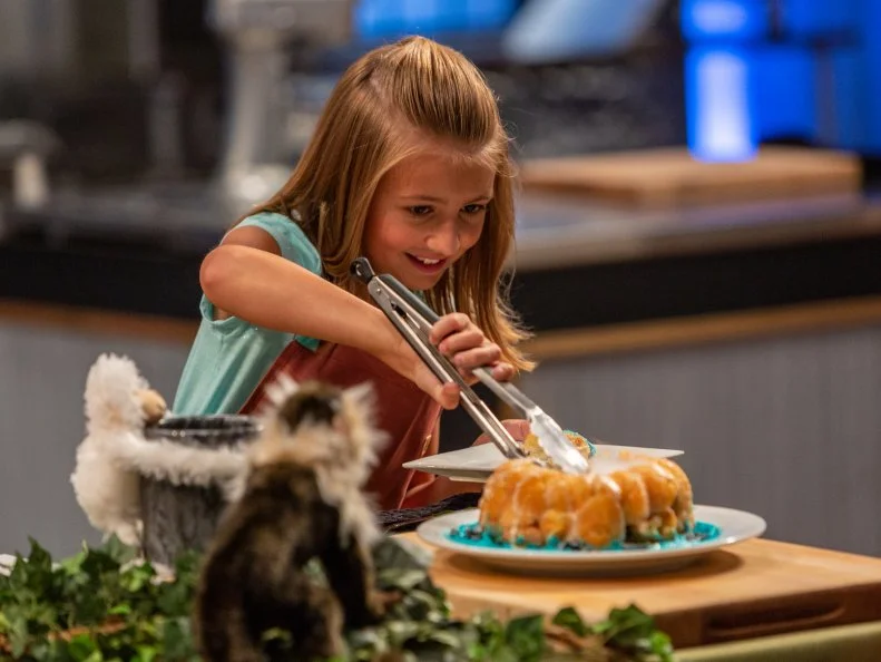Contestant Paige Goehner cuts her dish to present the to the judges, as seen on Kids Baking Championship, Season 6.
