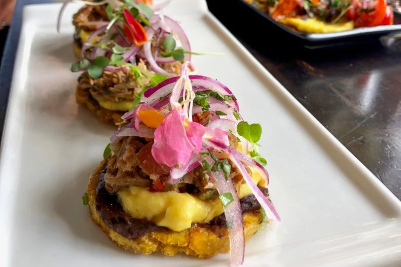 Fundamentally, tostones are just pressed, deep-fried green plantains — similar to a patacon, just made in smaller dimensions. It’s a common side starch, and not particularly flavorful. However, when chefs use tostones as a base or an edible vessel, like potato skins, snack magic happens. You might see them topped with shrimp and avocado, with pulled pork and pineapple, with vaca frita and beyond. At Coral Gables hot spot Seek & Find, tostones are on the appetizer menu topped with braised pork, mashed potato, black beans and an oniony salsa. They’re also served at brunch, replacing English muffins in the excellent Caribbean Benedict.