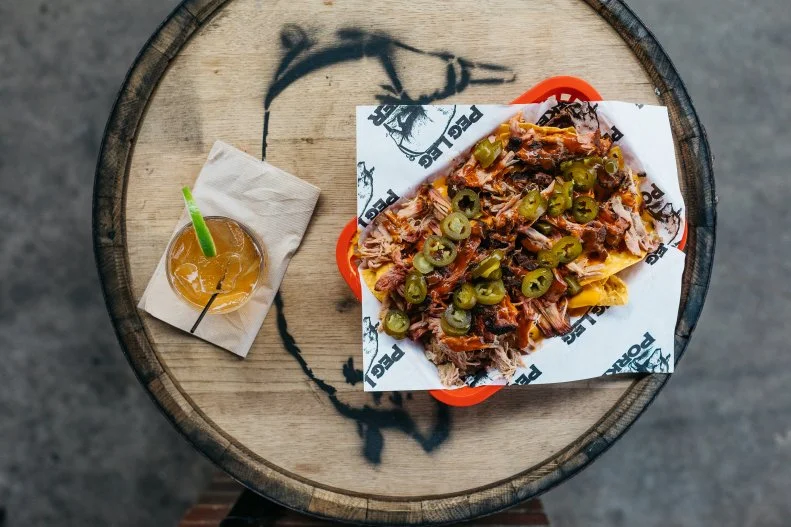 Pitmaster Carey Bringle (aka the Peg Leg Porker) knows good barbecue. After decades racking up awards and accolades on the competition circuit, the experienced pitmaster, who has deep roots in Tennessee barbecue, decided to open his own joint in the heart of Nashville’s Gulch neighborhood. After a recent update, the space is now sprawling, with a second-story patio and two full bars. Bringle’s dry ribs are some of the best in town, heavy on the seasoning and smoke. But don’t skip over the BBQ nachos, loaded with pulled pork, cheese sauce, and jalapenos, or the frozen drinks, some made with the pitmaster’s award-winning Peg Leg Porker Tennessee Straight Bourbon Whiskey.