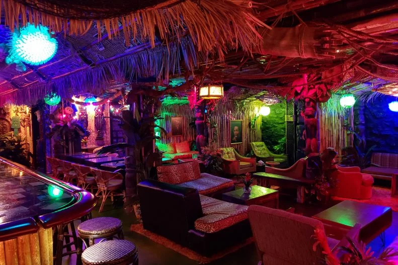 It isn’t easy to find this tiki-inspired speakeasy. Located in the basement of craft beer bar Hopcat, the only way to enter Tiki Cat is to find the door behind the bamboo wall. The intimate space is made up of retro huts with cool vintage furniture and shag carpet all designed by tiki expert “Bamboo” Ben Bassham.  The cocktails – with all of the juices and syrups made on site – range from the classics like the Painkiller with fresh coconut cream, fresh squeezed pineapple juice and orange juice, fresh-grated nutmeg and plenty of rum, to more creative cocktails like the Cat Bird Seat made with three types of rum, blackberry brandy, fresh lemon and lime juice, orange Curacao, demerara syrup, and orange bitters.