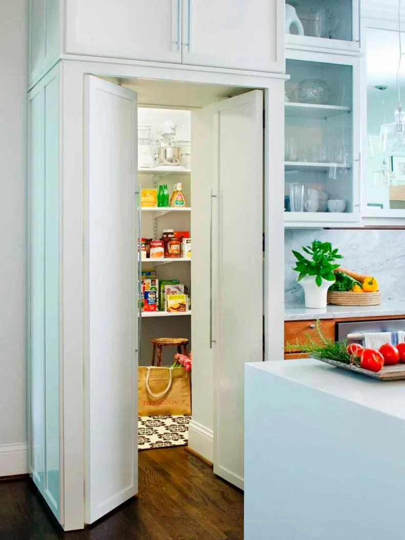 This contemporary kitchen has a large walk-in pantry built into the cabinetry for optimal hidden storage space. Just outside the pantry, a marble backsplash and sleek kitchen island complete the modern look of the space.