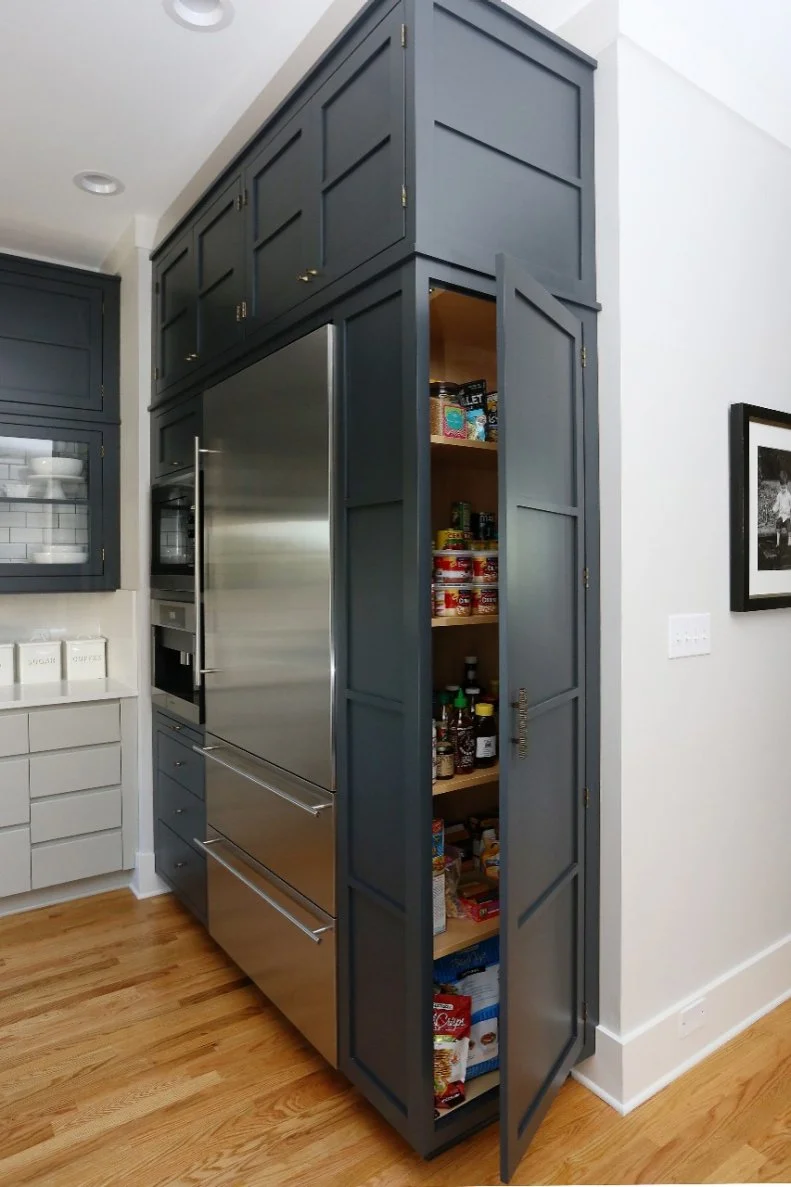 Making the most of every corner, a pantry is installed in the cabinet that houses the stainless steel refrigerator. Floor-to-ceiling cabinetry also provides tons of much-needed storage in this kitchen, which is truly the heart of the home.  