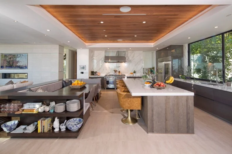 To separate this kitchen from the living room, a low banquette wraps around a dining table. The sight line across the floor stays clear and there's even built-in shelving at one end for extra storage.