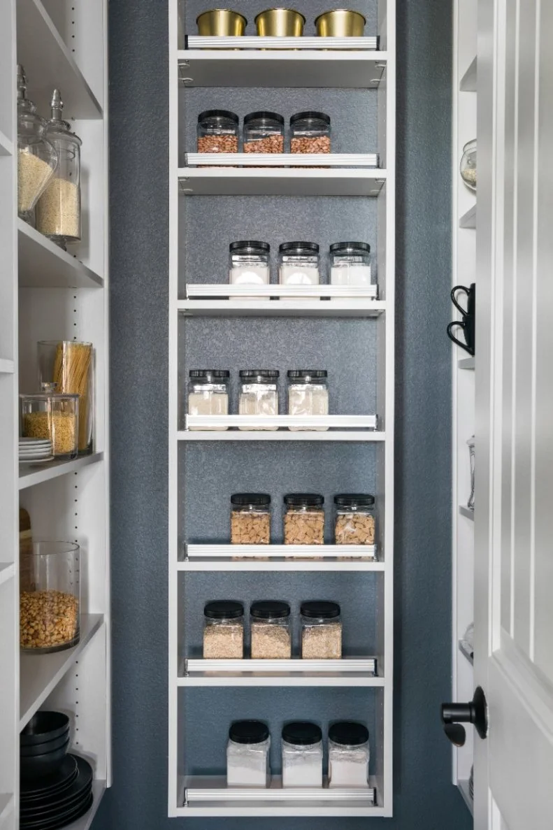 The back wall of the walk-in pantry has a wall-mounted rack with space for cannisters of assorted dry goods. Adding labels to the cannisters makes it easy to quickly find ingredients when making nightly dinner or a special occasion meal. 