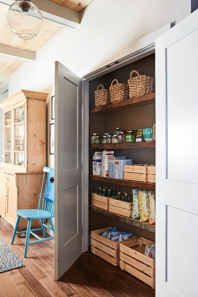Classic white doors conceal a well-organized pantry. Wooden boxes, glass jars and woven baskets add beauty and function to this storage space.