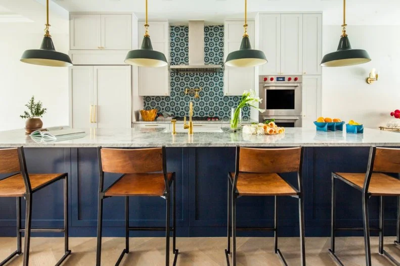 White cabinets let the fun patterned backsplash pop in this lovely kitchen. The green pendants and blue island bring the rich colors out into the room.