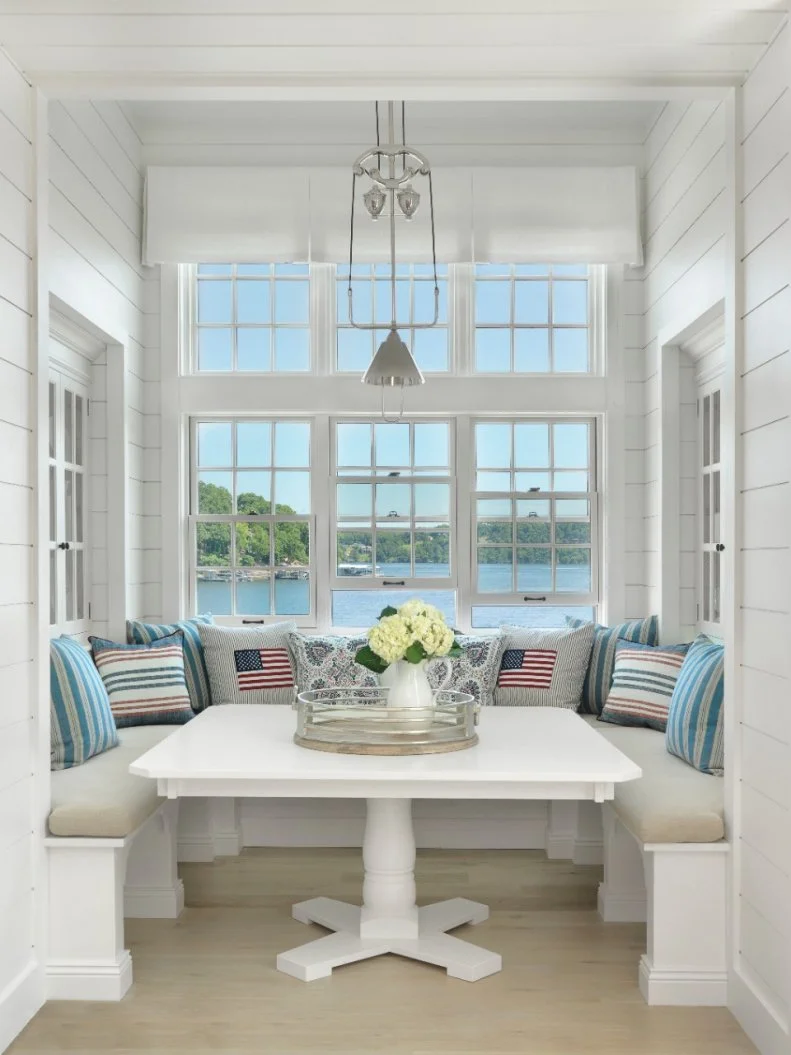 The design inspiration for this breakfast nook started with the light fixture, discovered in a Nantucket shop. To cozy up the banquette, red, white and blue pillows were added for a touch of Americana. 
